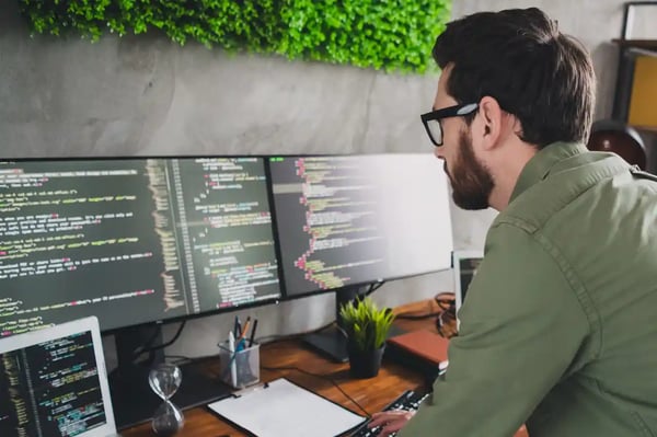 Un développeur Symfony consulte le code d'une application sur plusieurs écrans