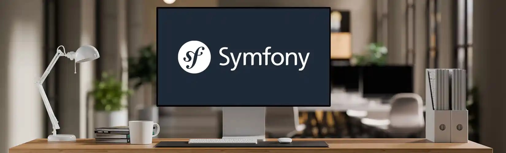 Un open space avec un écran d'ordinateur affichant le logo du framework Symfony sur un fond gris foncé