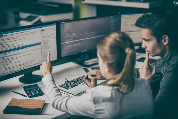 Une développeuse web échange avec son collègue au sujet d'un projet. Elle lui montre le rendu du code lors de l'inspection du projet.