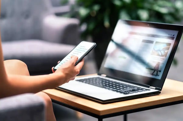 Une personne consulte un site web sur son téléphone portable et sur son ordinateur