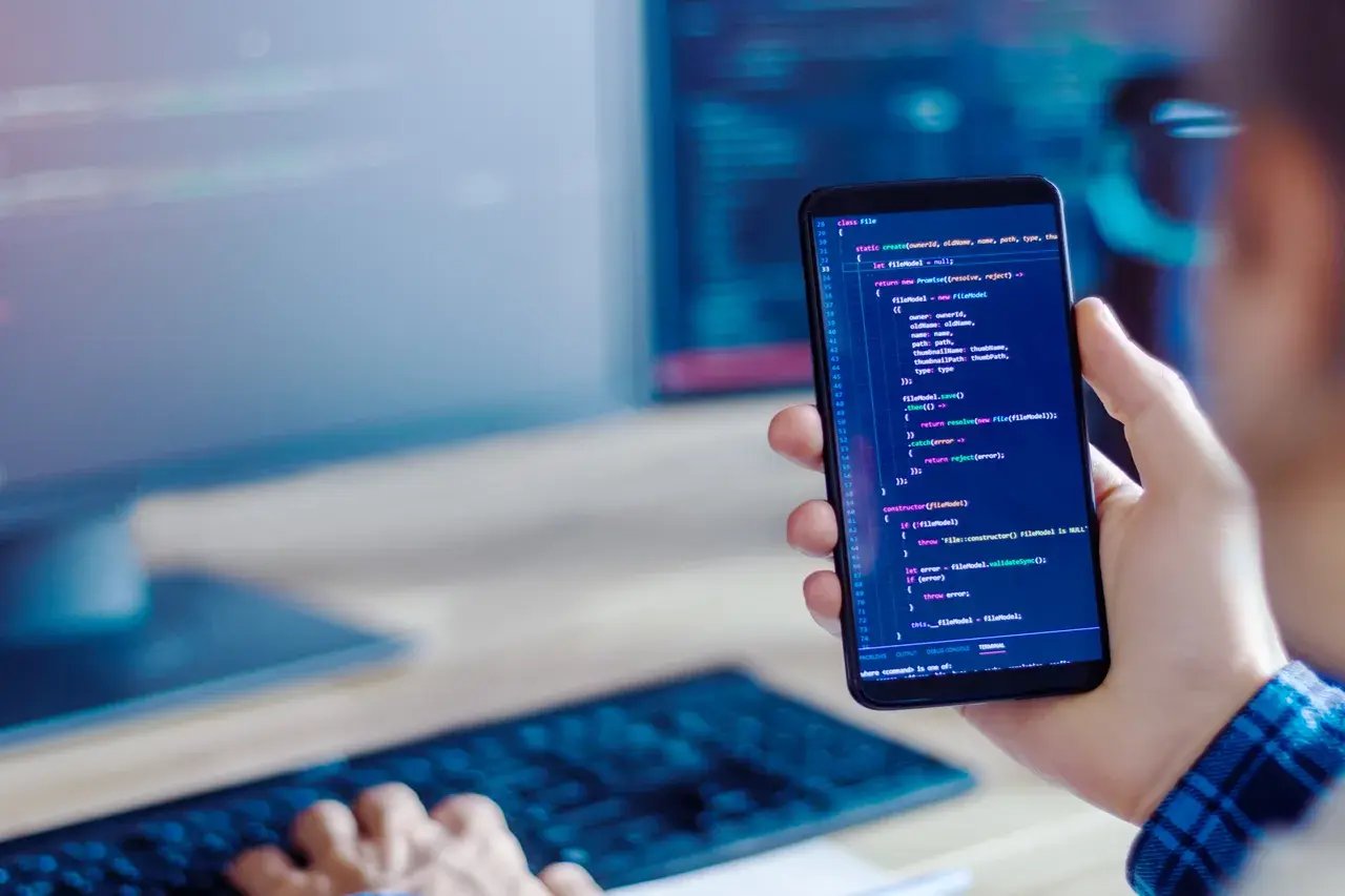 Un développeur regarde le code d'une application métier développé avec le framework Symfony sur un téléphone portable