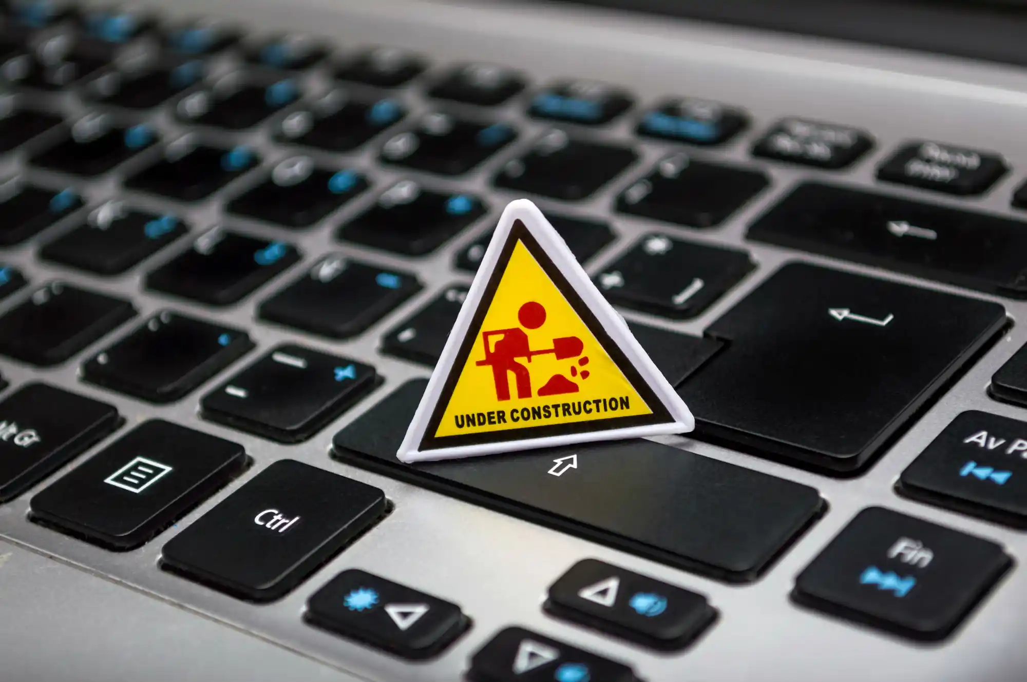 Image montrant un clavier d'ordinateur avec un petit panneau jaune "en maintenance"